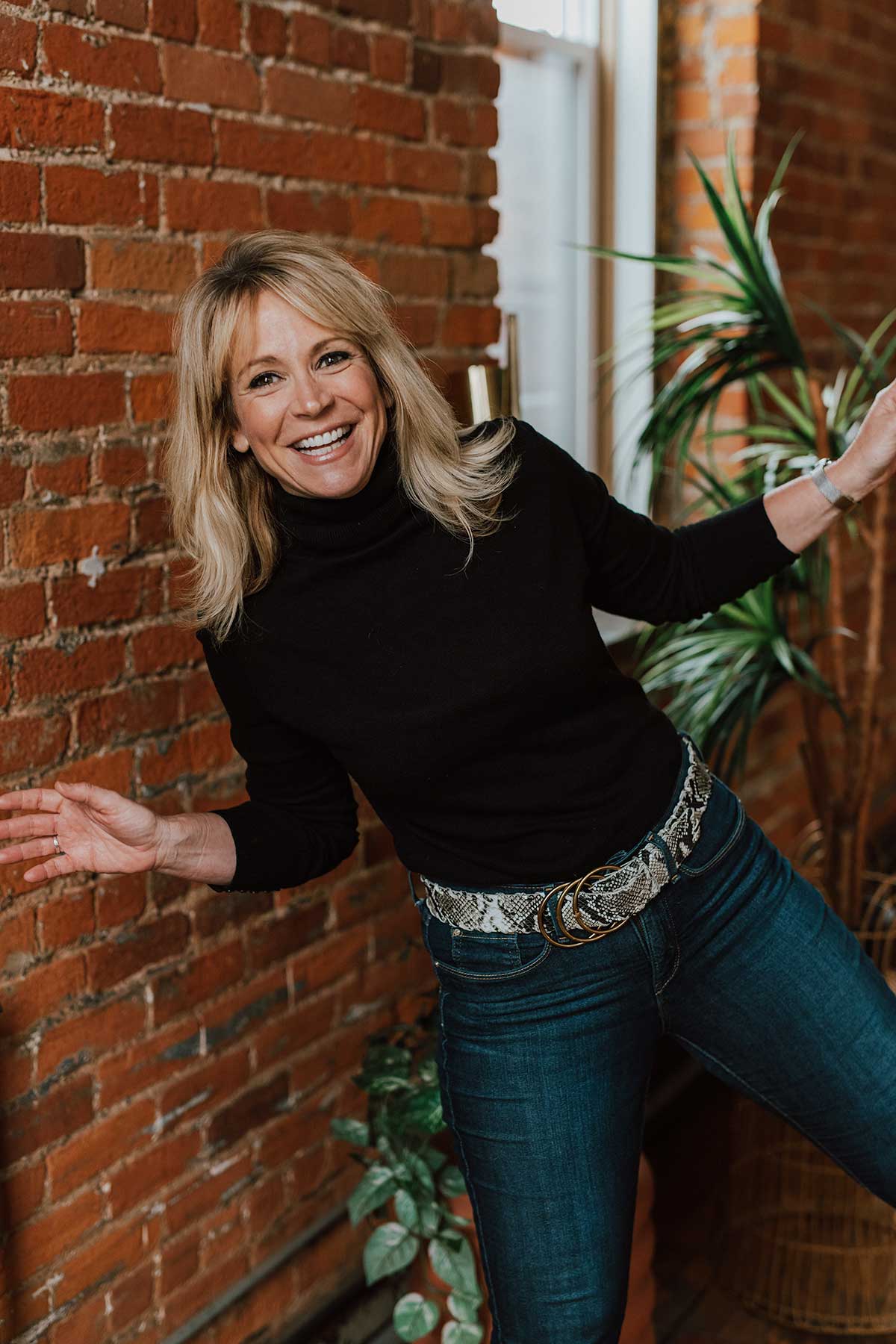 Debbie Truman photo with black turtleneck with brick wall background